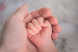 a baby hand inside of the moms hands